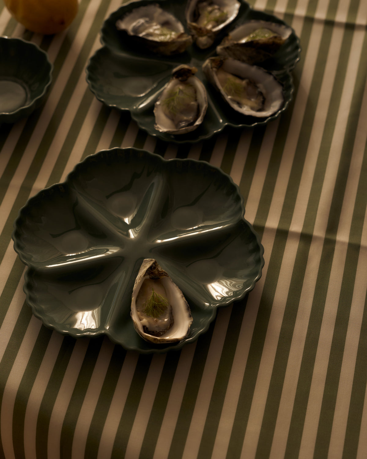 Mother of Pearl Oyster Plate, Half Dozen, in Dark Forest Green, styled on a table. Photograph by Lillie Thompson