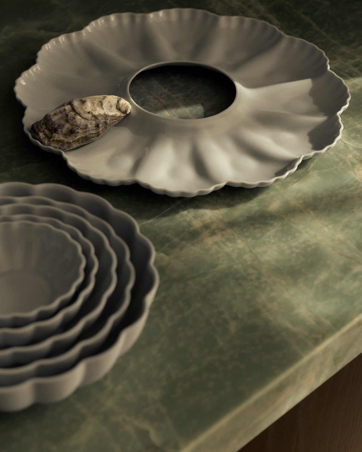 Mother of Pearl Oyster Plate, Dozen, in Light Blue Grey, styled on a table. Photograph by Lillie Thompson