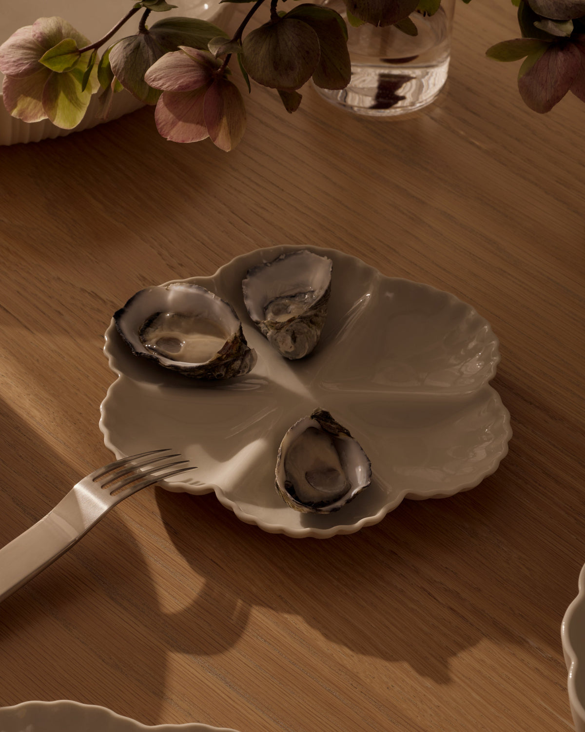 Mother of Pearl Oyster Plate, Half Dozen, in Natural White, styled on a table. Photograph by Lillie Thompson