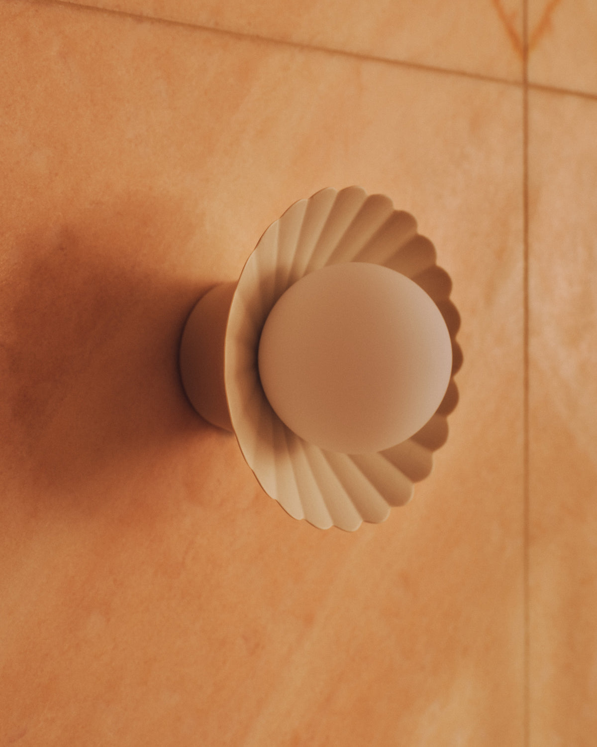 Daisy Wall Sconce in Natural White on a tiled wall, close up. Photograph by Sarah Forgie