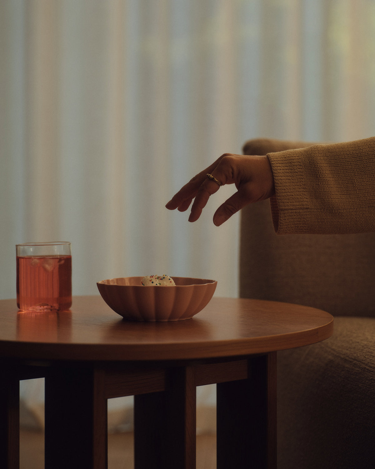 Fern Nesting Bowl in Whispery Pink on a side table, a hand reaching in. Photograph by Sarah Forgie