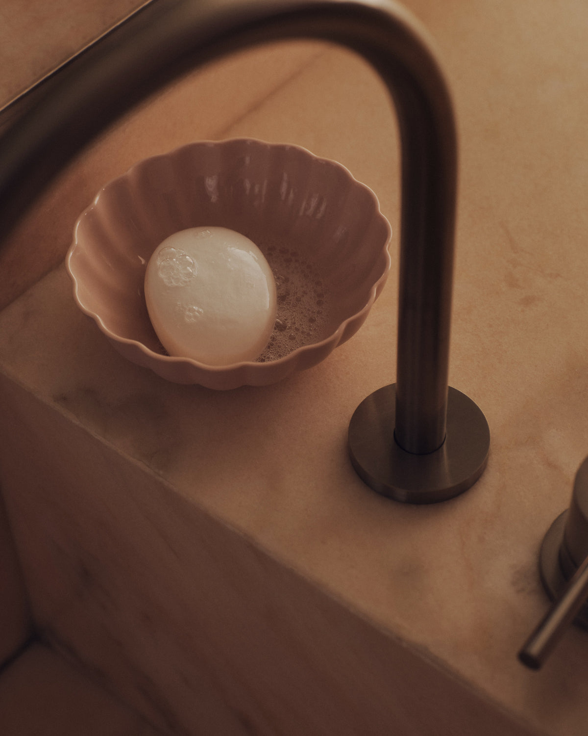 Fern Nesting Bowl 15cm Medium in Whispery Pink beside a tap. Photograph by Sarah Forgie