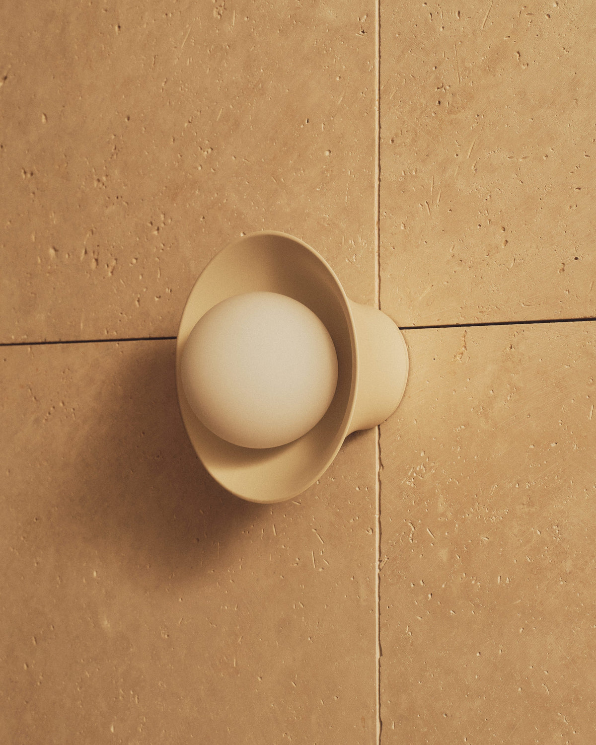 Natural White Pixie Wall Sconce on a travertine wall. Photograph by Sarah Forgie